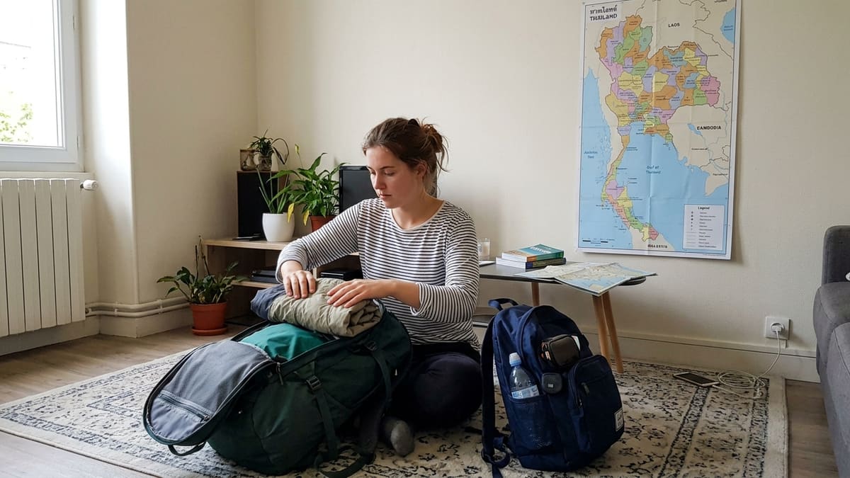 Femme organisant son sac à dos de voyage en Thaïlande, avec un petit sac d’appoint prêt pour le bus